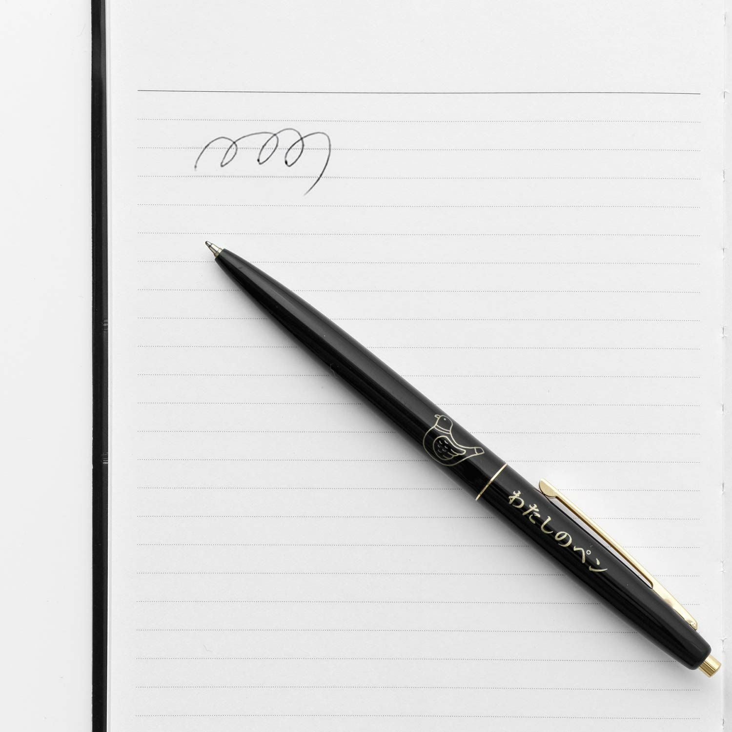 Black pigeon flute pen resting on a lined notebook page with handwritten scribbles.