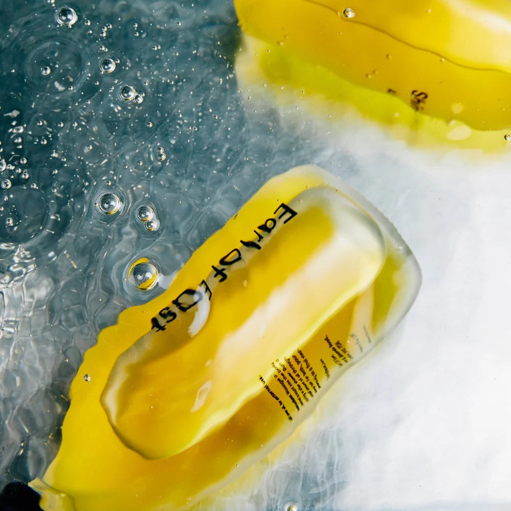 Bottles of Earl of East Shinrin-Yoku All Over Oil submerged in water with bubbles, seen up close.