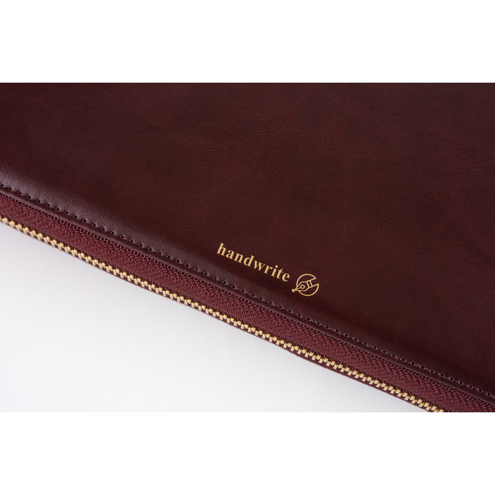 Close-up of Amarone leather book cover with gold "handwrite" foil stamp and gold zipper along the edge