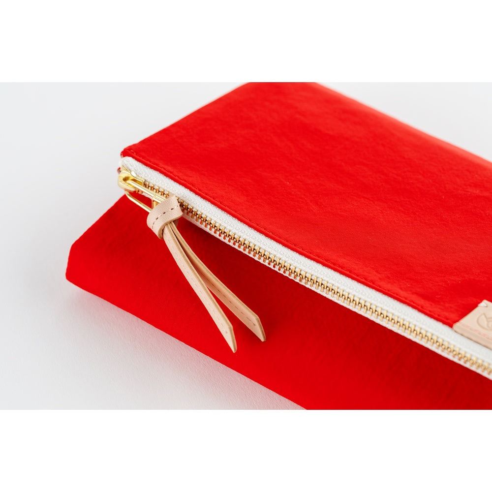 Close-up of a Red Hobonichi book cover showing its gold zipper with light leather pull tab.