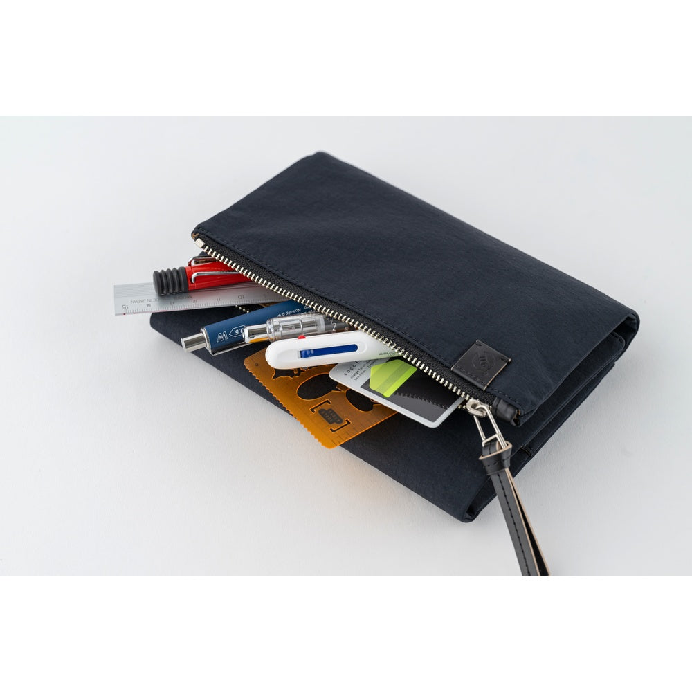 Hobonichi Tragen A6 book cover in Black, unzipped to reveal pens, a ruler, cards and wrist strap.