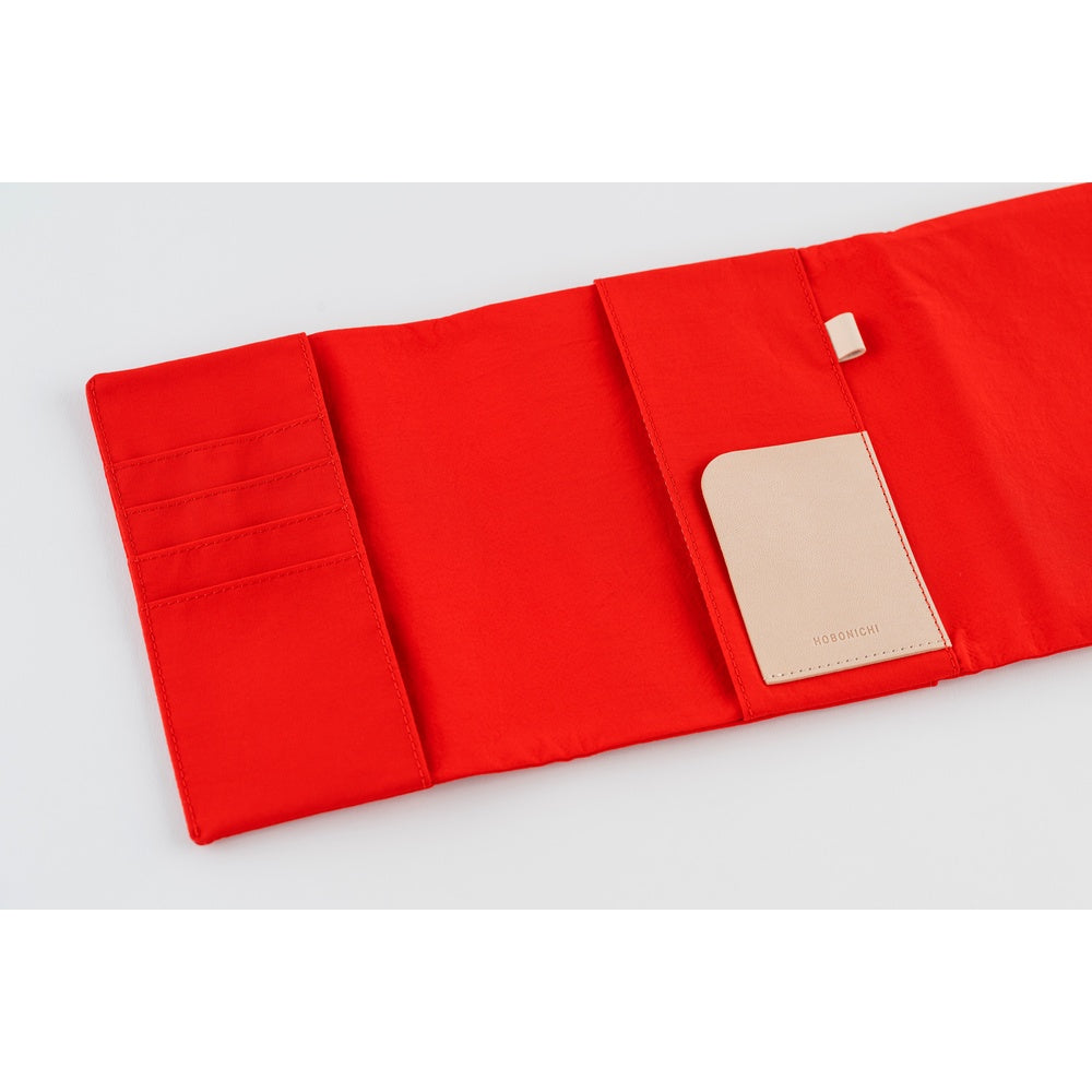 Hobonichi A6 book cover opened flat, showing Red fabric interior with card slots and a beige pocket