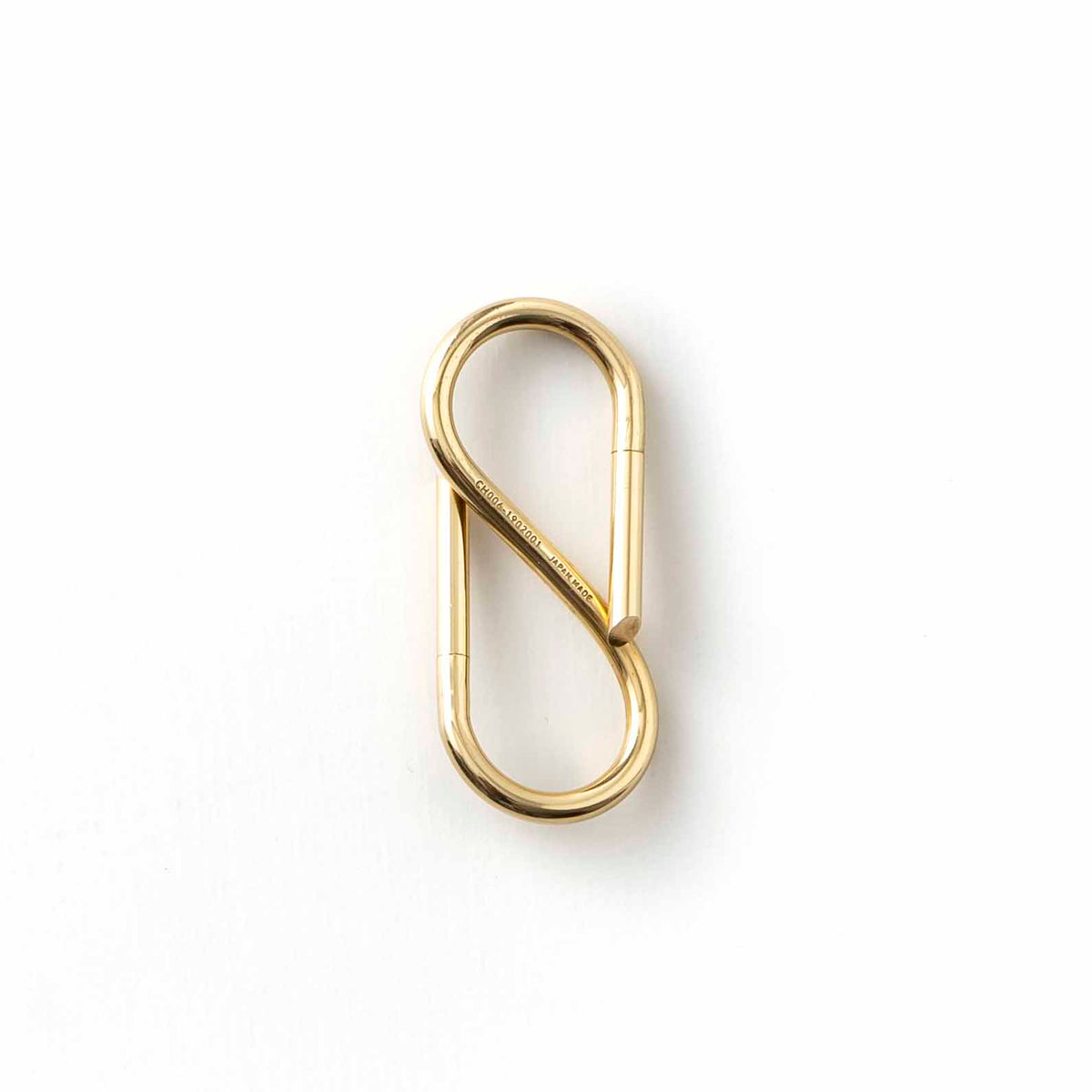 S-shaped Brass key ring with two rounded loops and engraved lettering along the center bar.