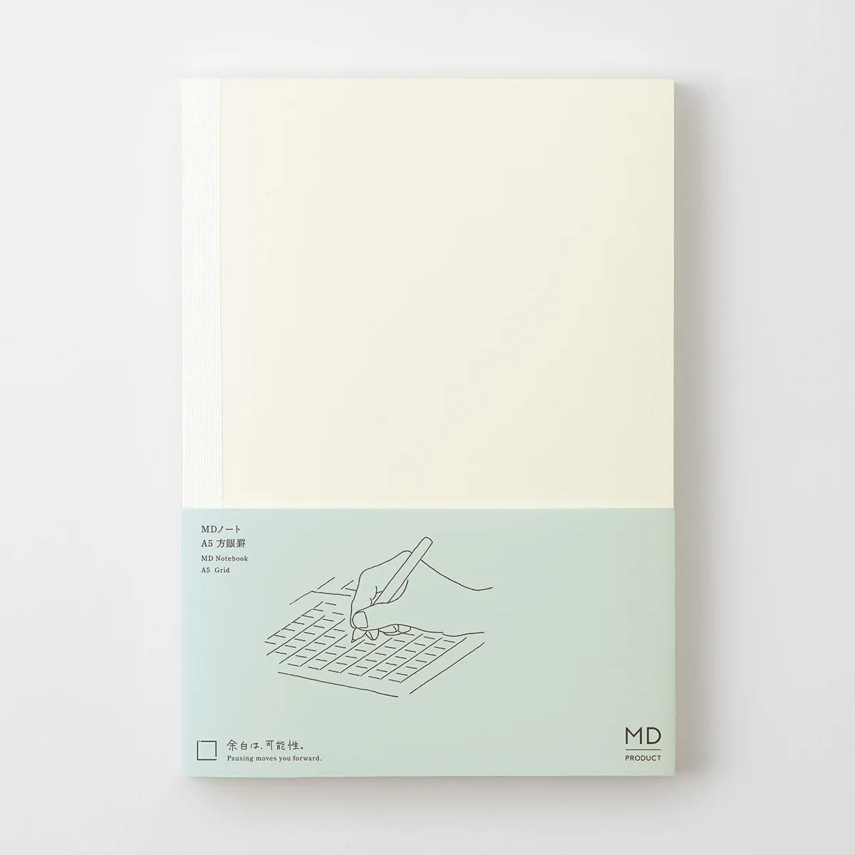 Midori MD Notebook A5 grid with plain cover and pale blue paper band showing a hand writing on a grid.