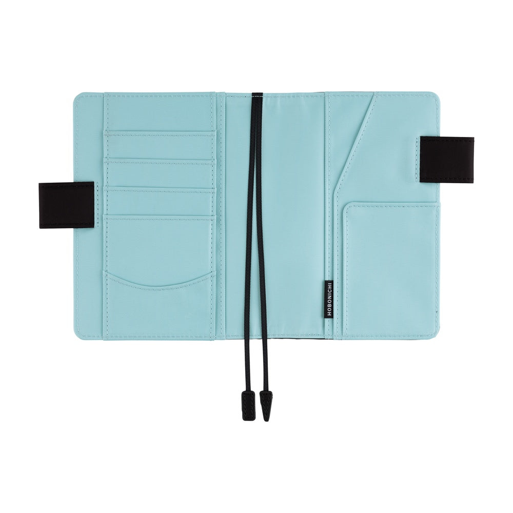 Hobonichi A6 book cover opened flat, showing light blue interior with card slots, pockets and black bookmarks