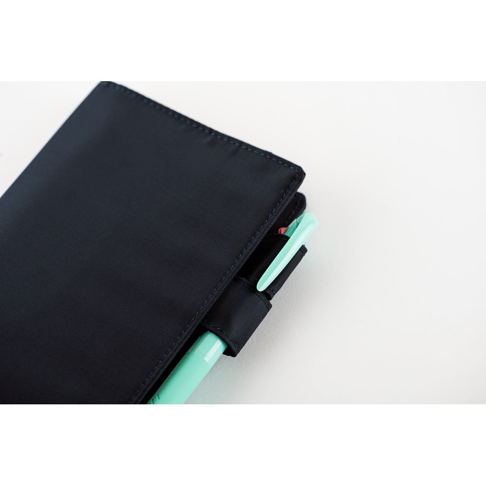Close-up of Black Hobonichi A6 cover's side pen loop holding a mint green pen against a white background.