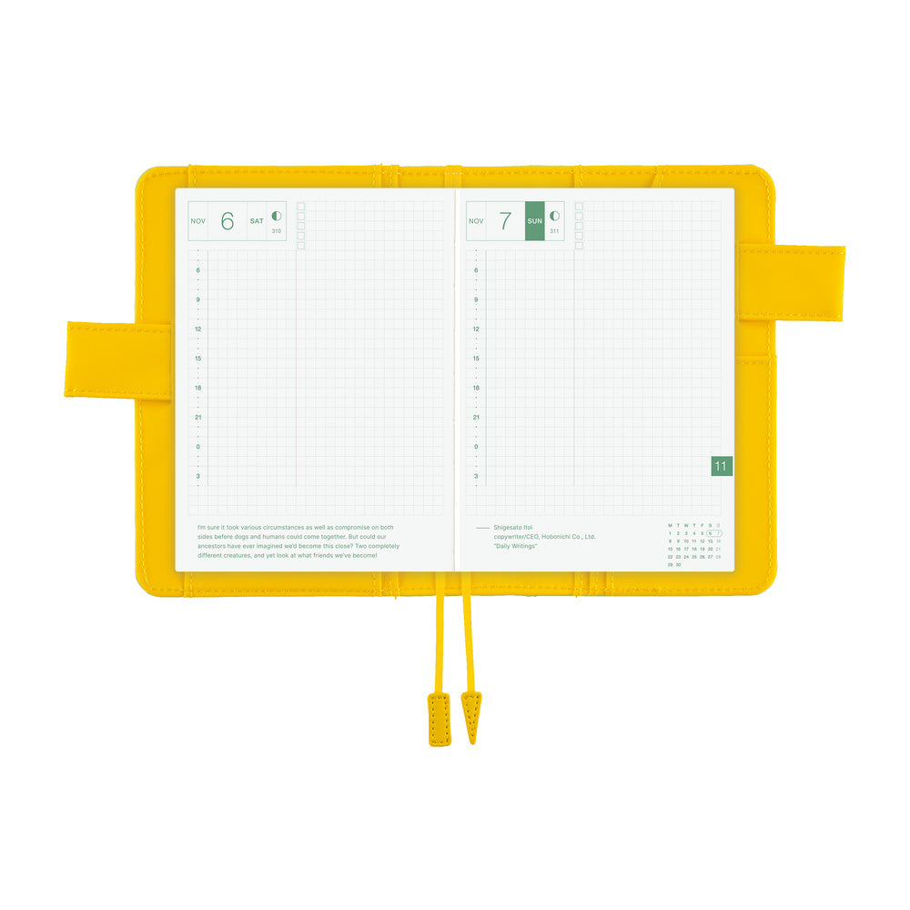 Hobonichi A6 book cover in Fresh Citron, opened flat to show grid daily pages and two yellow bookmarks.