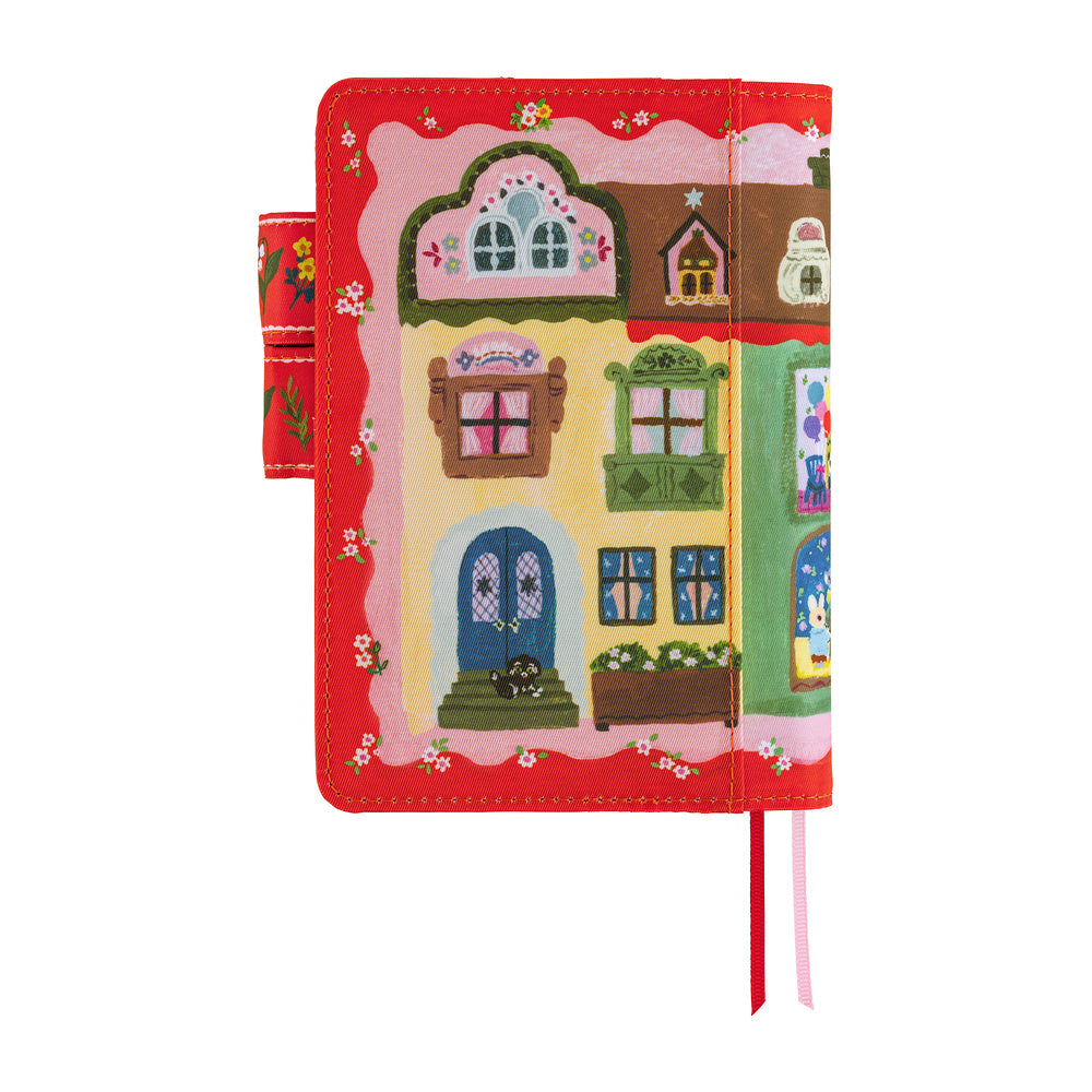 Red Hobonichi A6 planner cover illustrated with storybook houses, windows and flowers, with ribbon bookmarks