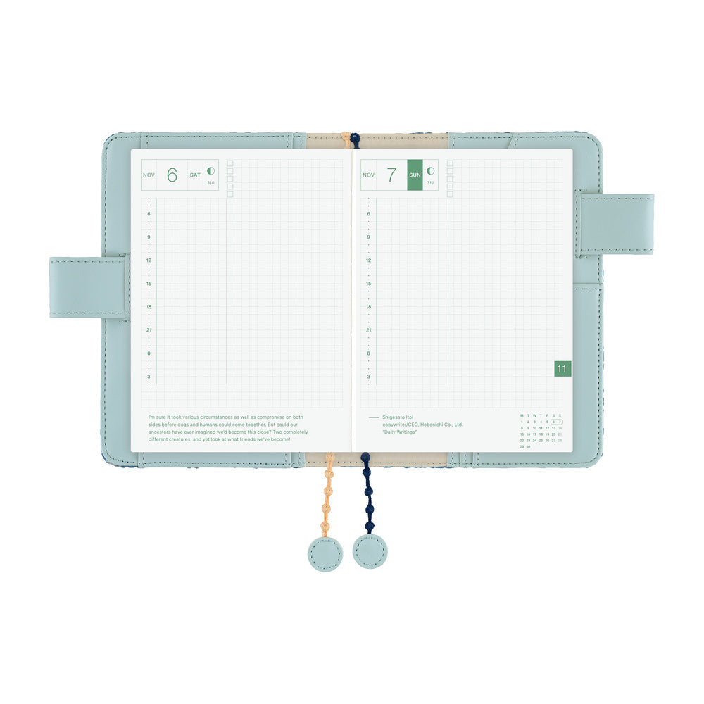 Open A6 planner in Blue book cover, showing grid daily pages with side flaps and two beaded bookmarks.