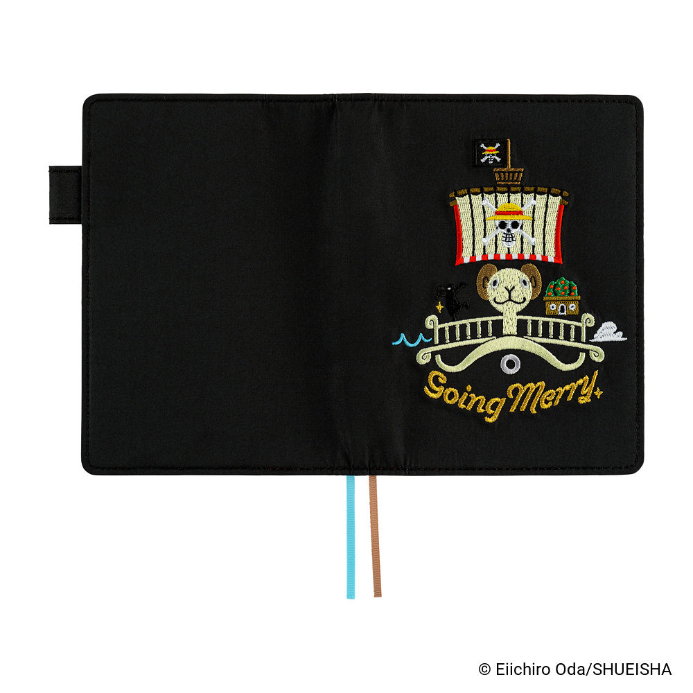 Black A6 book cover opened flat, embroidered Going Merry ship design, with blue and brown bookmarks.