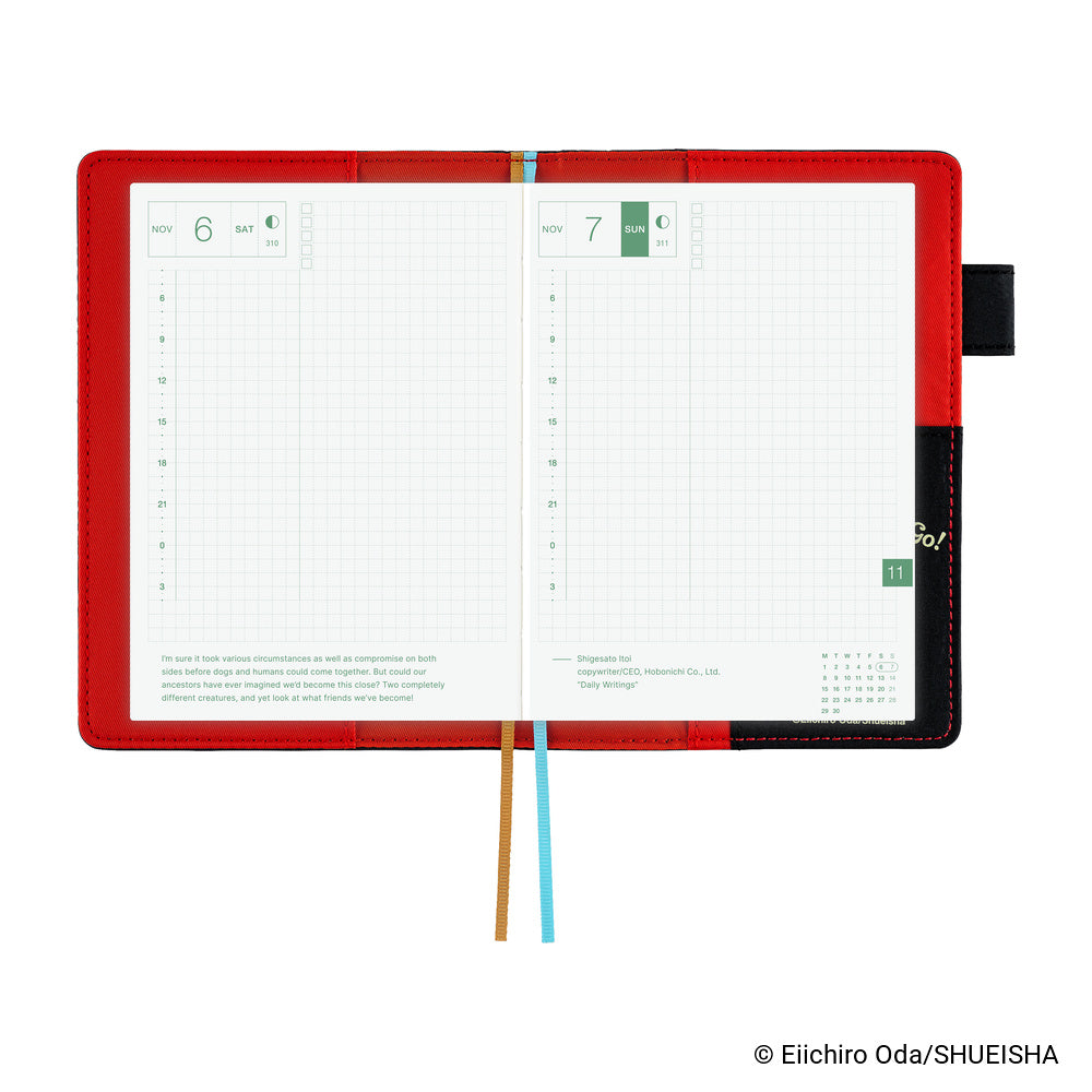Hobonichi A6 book cover opened flat, showing red interior lining, grid daily pages and two ribbon markers.