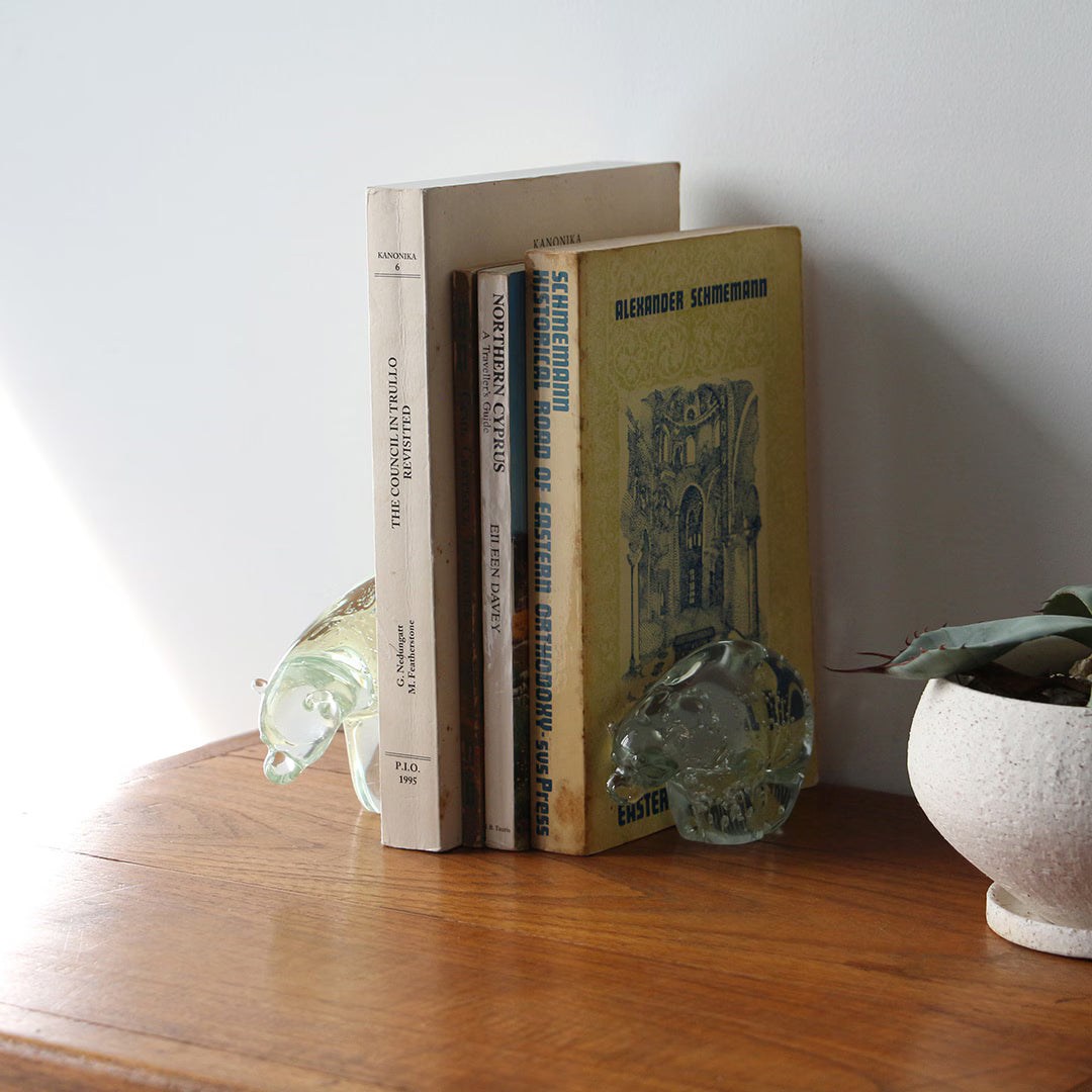 Clear glass polar bear objects used as bookends holding books upright on a wooden surface