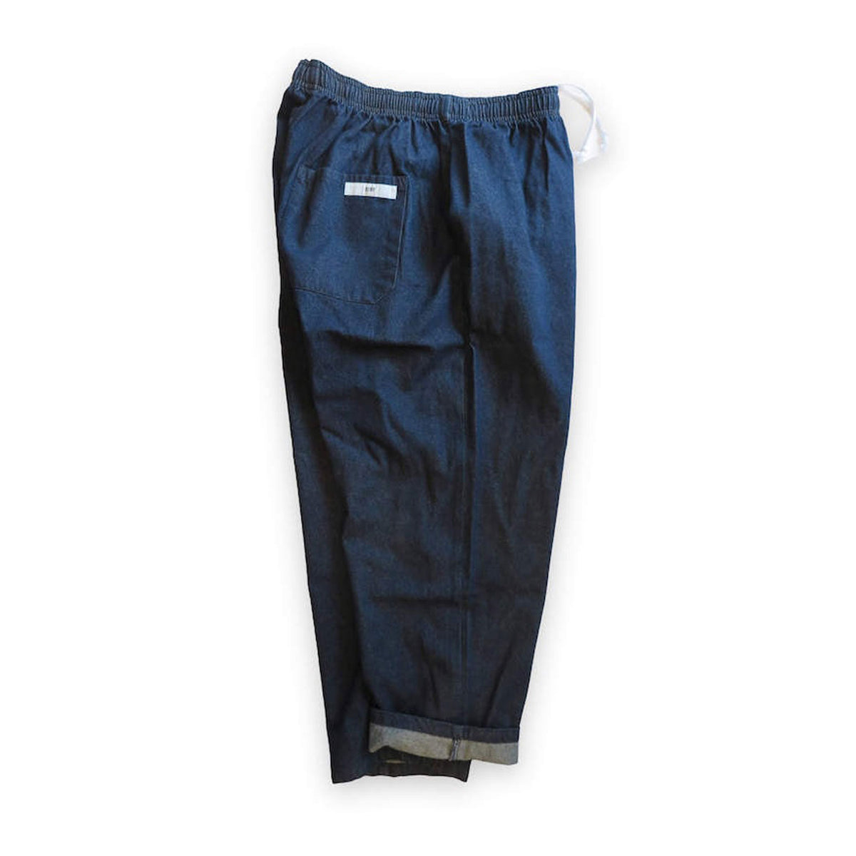 Voiry Sunday Pants in Dark Blue denim laid flat, back view with patch pocket, elastic waist and cuffed hem.