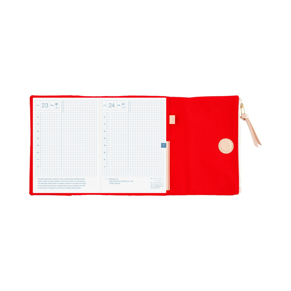 Hobonichi A6 book cover in Red, opened flat to grid-ruled daily pages beside a zippered pouch panel.