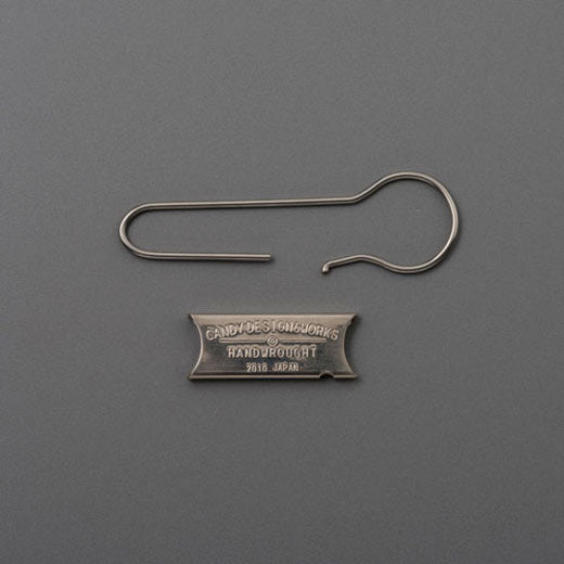 Candy Design & Works metal key ring with a hooked pin clasp, shown beside a stamped brand plate.