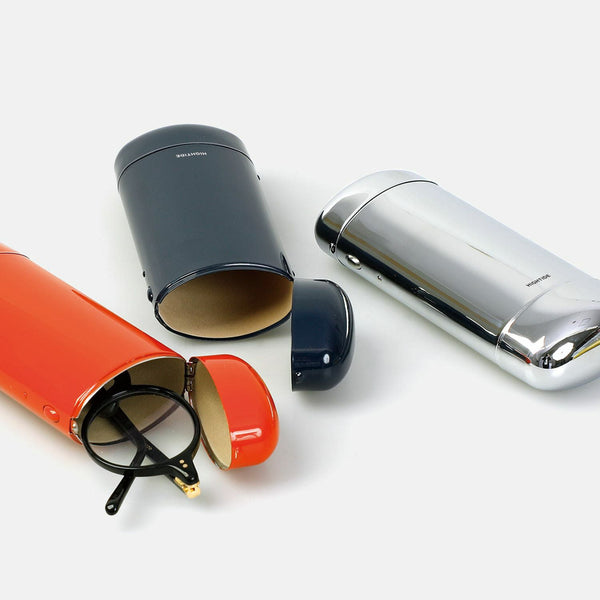 Three Hightide cylindrical glasses cases in Red, Black and Silver, two open with round glasses beside them.