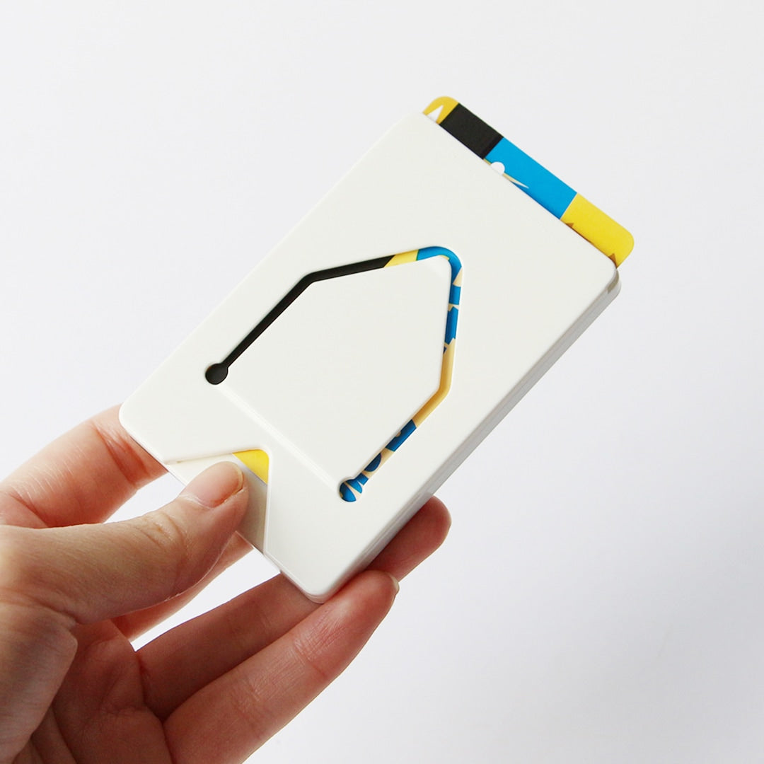 Hand holding a slim white card case with a thumb slot, colorful cards visible inside.