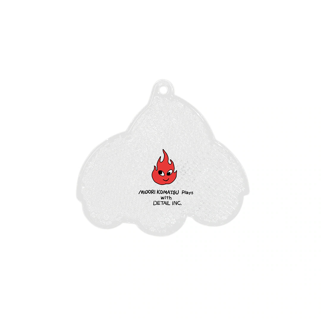 Back of white ghost-shaped reflector keychain with red flame illustration and Midori Komatsu text.