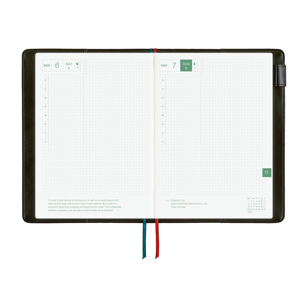 Open A5 planner in a dark cover, showing grid daily pages for Nov 6 and 7 with blue and red bookmarks