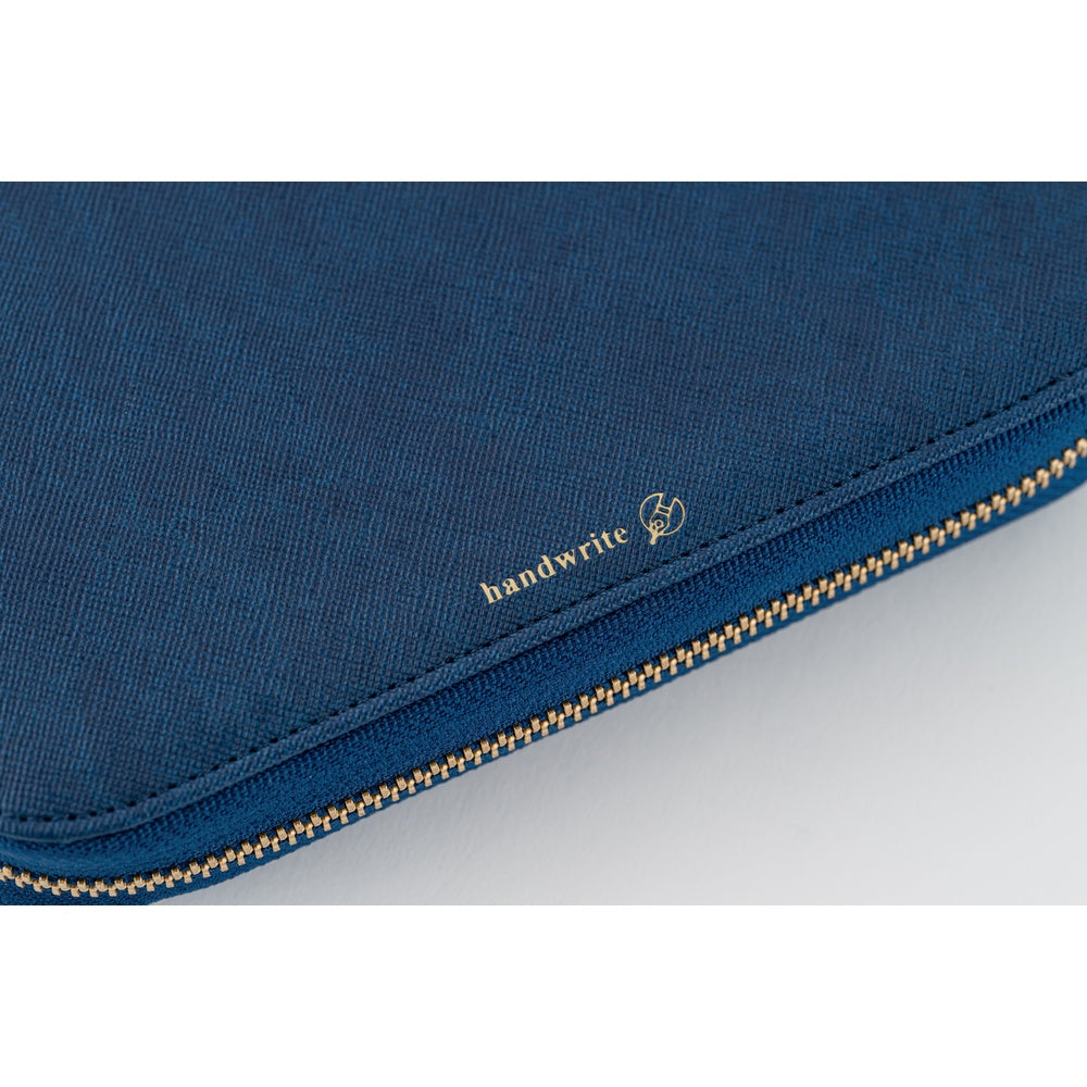 Close-up of Lago blue fabric book cover corner with gold zipper and gold "handwrite" lettering