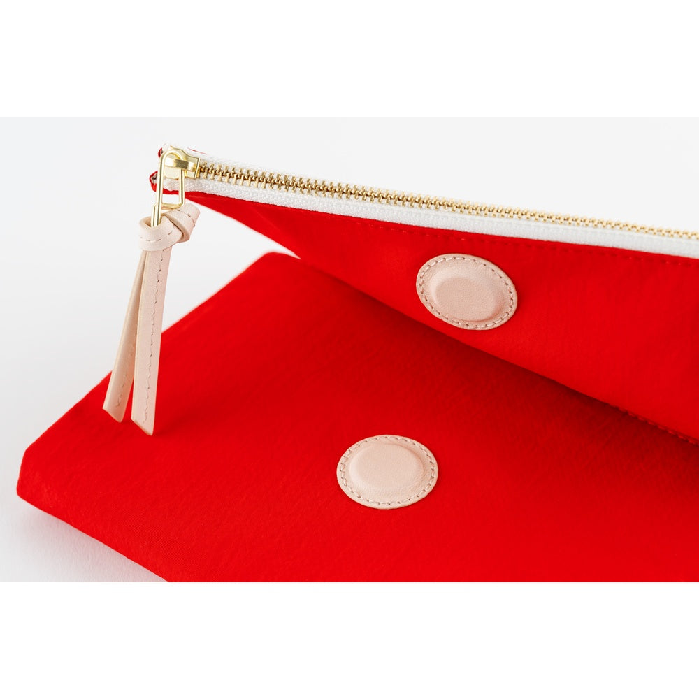 Close-up of Red book cover showing gold zipper, leather pull tab and round pale leather snap details.