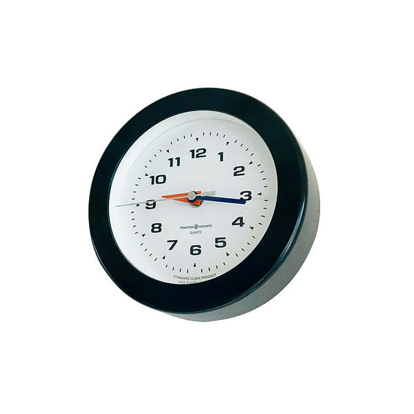Angled view of the Carlo Mini Clock, a Black round wall clock with white dial and blue and orange hands.