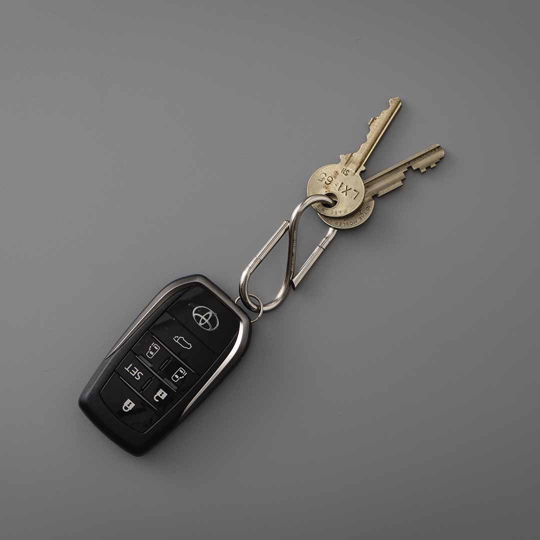 S-shaped Nickel key ring holding two brass keys on a ring and a black car smart key fob.