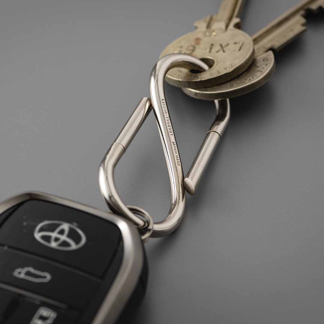 Close-up of the Nickel S-shaped key ring holding brass keys on one end and a car key fob on the other.