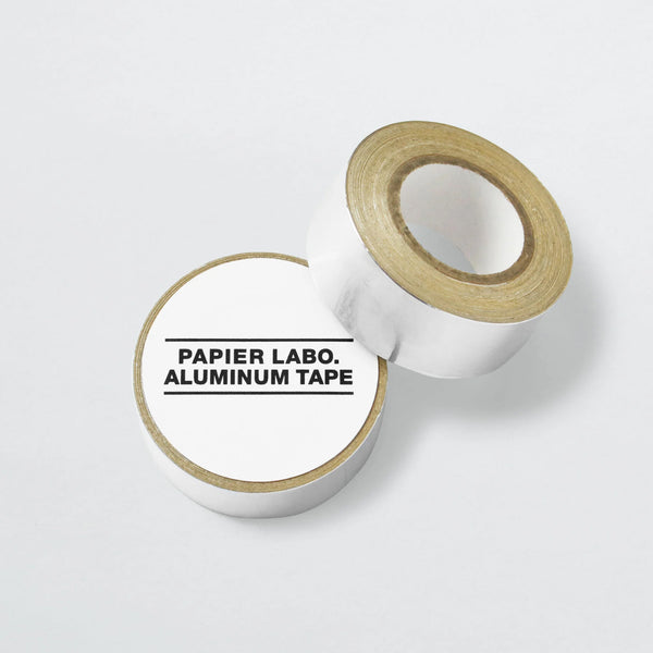 Two rolls of Papier Labo. silver aluminum tape, one upright and one lying flat with a printed label.