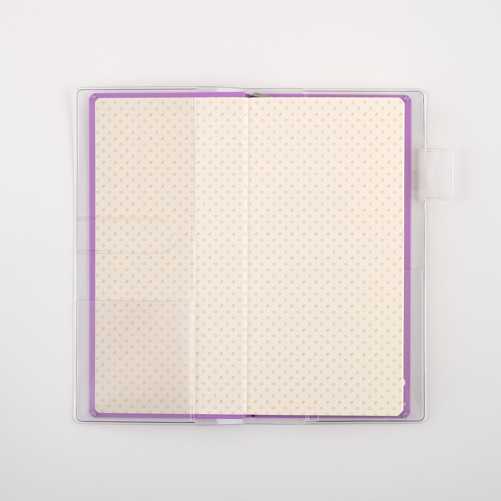 Clear plastic cover fitted over an open purple-edged Hobonichi Weeks planner with patterned pages