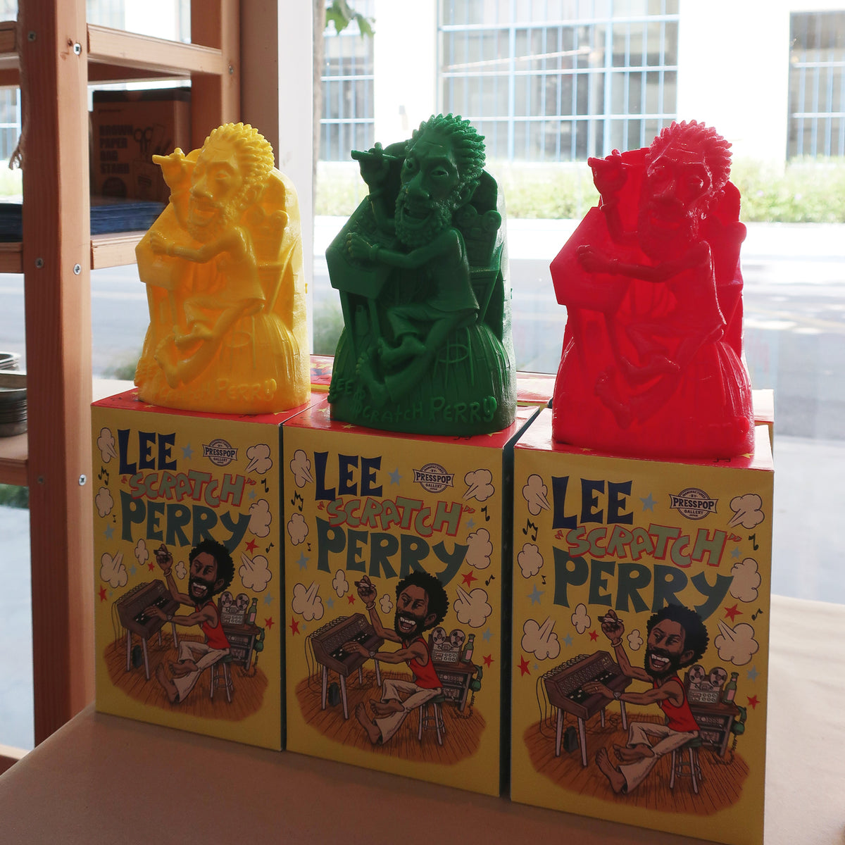 Lee "Scratch" Perry vinyl figurines in Yellow, Green and Red displayed on their illustrated boxes.