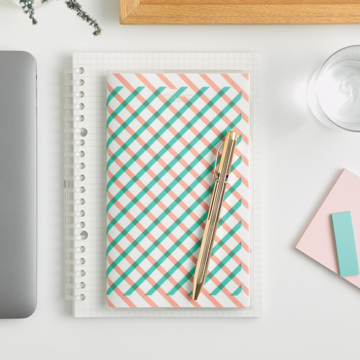 Green and pink checked B6 slim planner on a grid notebook with a gold pen resting on top.