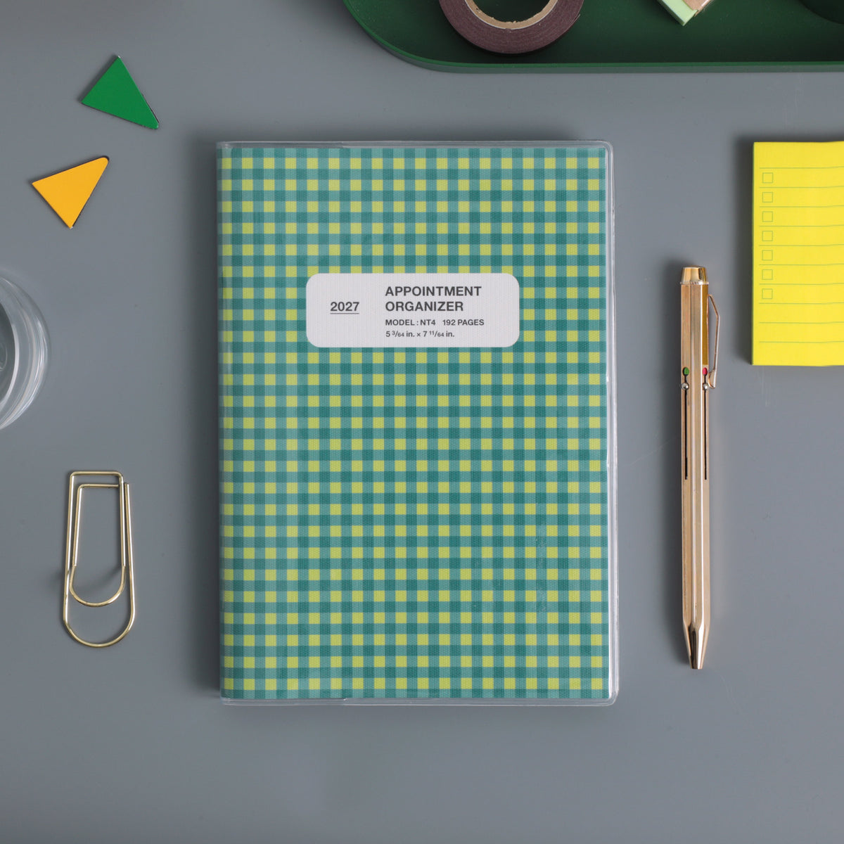 Hightide 2027 Reno B6 weekly planner in Green check pattern with clear cover, beside a pen and paper clip.