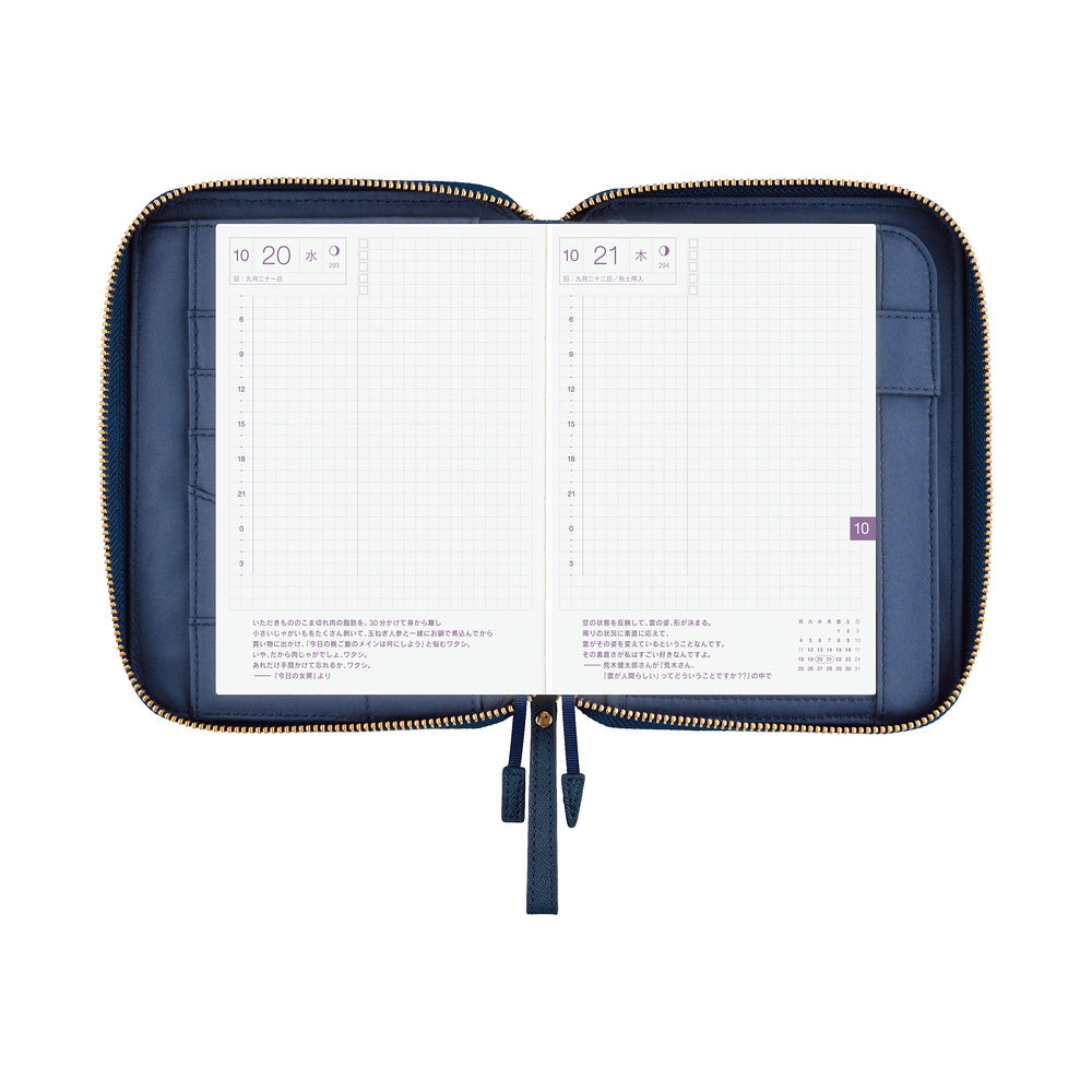 Navy blue zip-style A6 book cover opened flat, showing daily planner pages and two ribbon pulls.