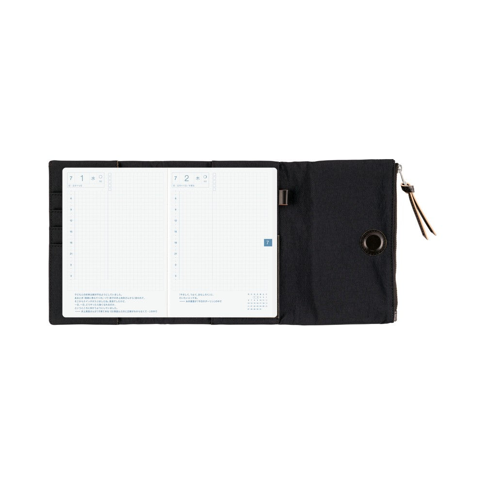 Open Black Hobonichi Tragen book cover showing grid daily pages, pen loop, zipper pull and eyelet.
