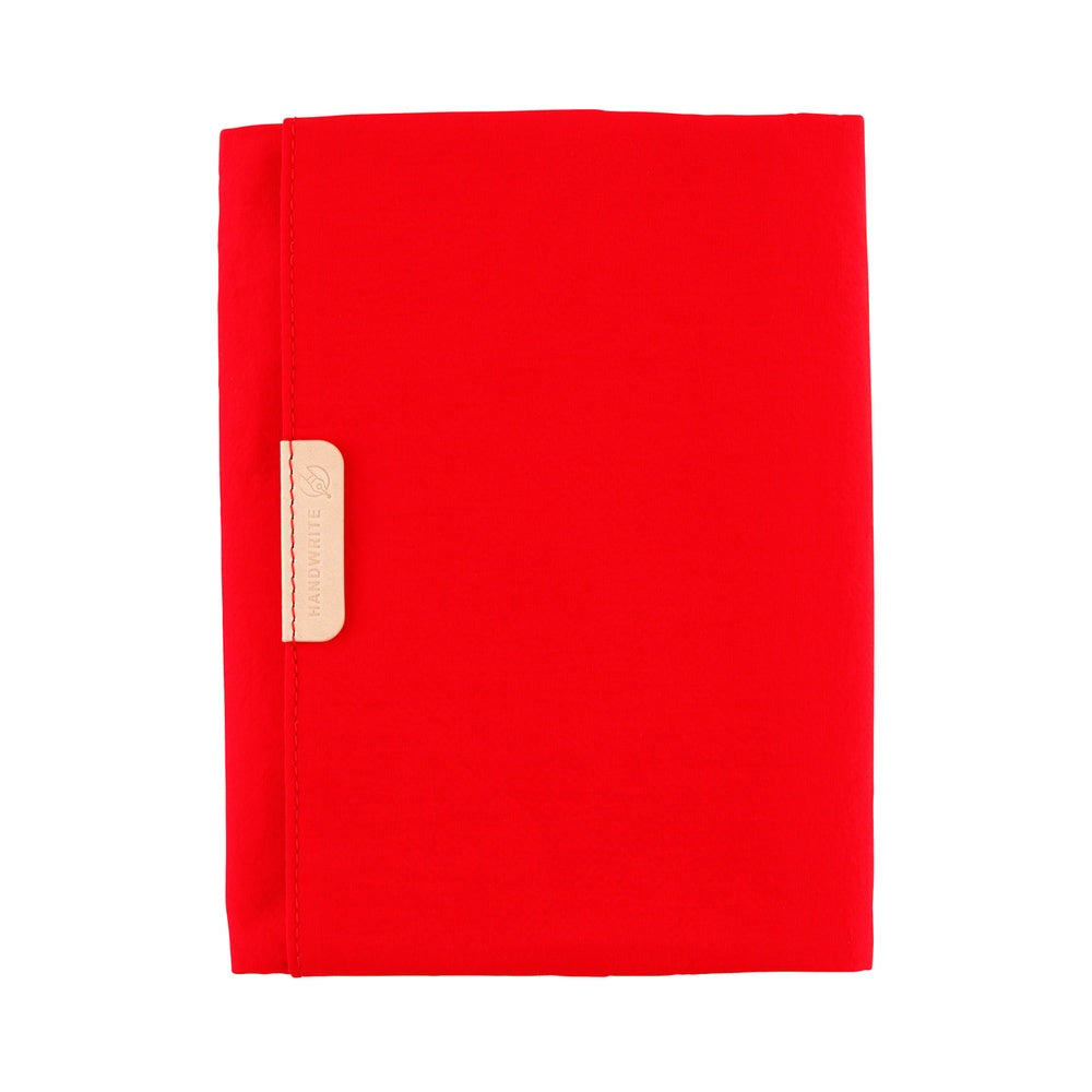 Hobonichi A6 Tragen book cover in Red, closed flat with a pale leather tab tag on the front panel.