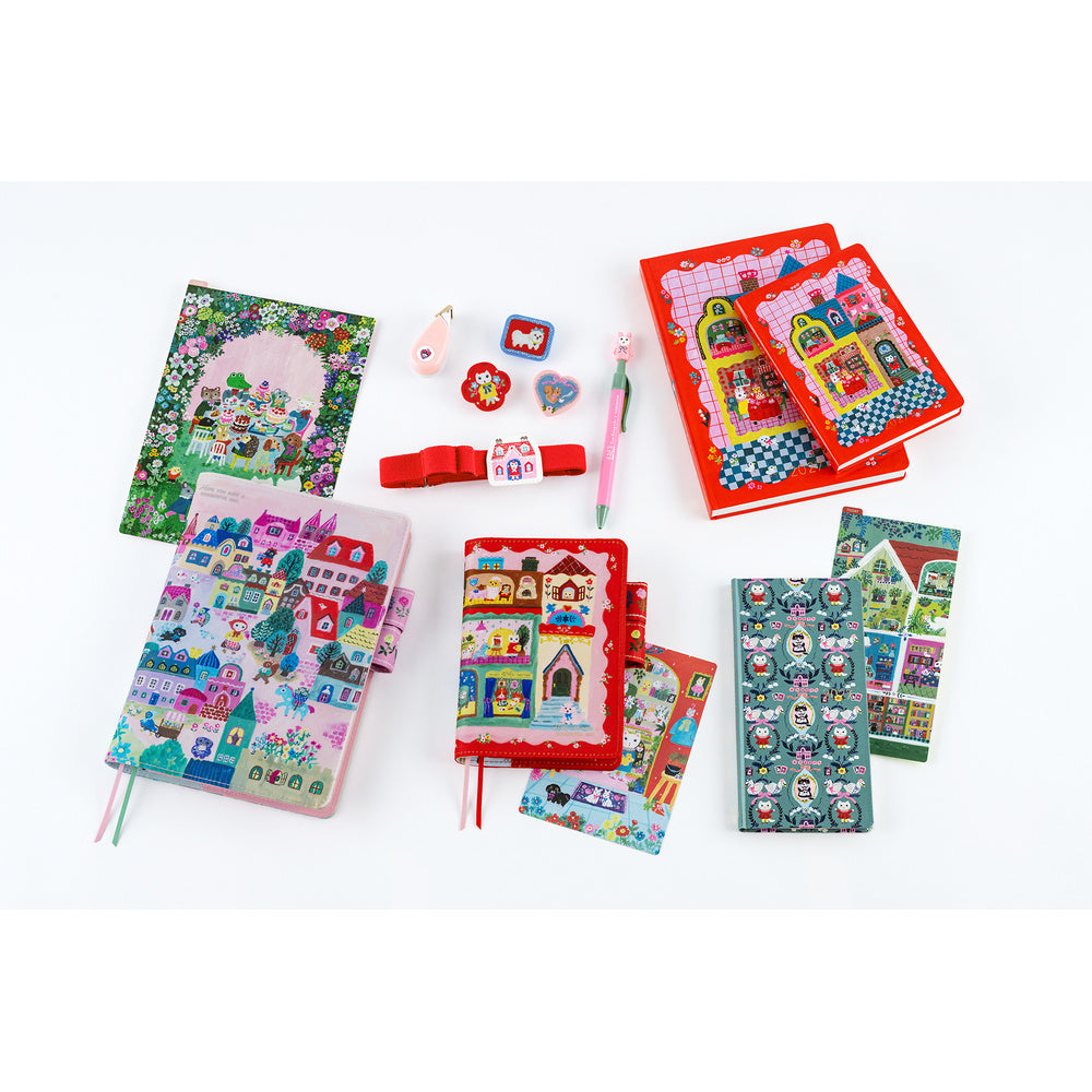 Flat lay of Hobonichi Yumi Kitagishi illustrated planner covers, notebooks, pen, erasers and Red band