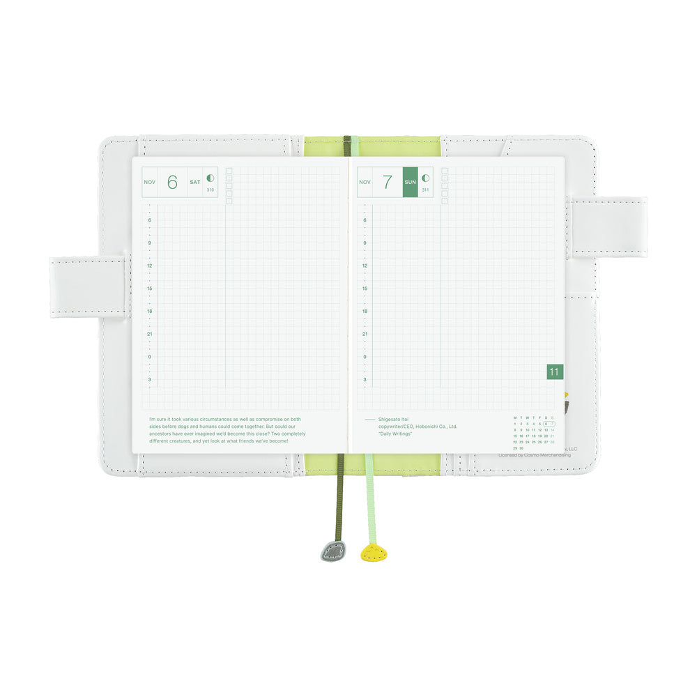 White A6 book cover open flat, showing grid daily pages with green accents and two ribbon bookmarks.