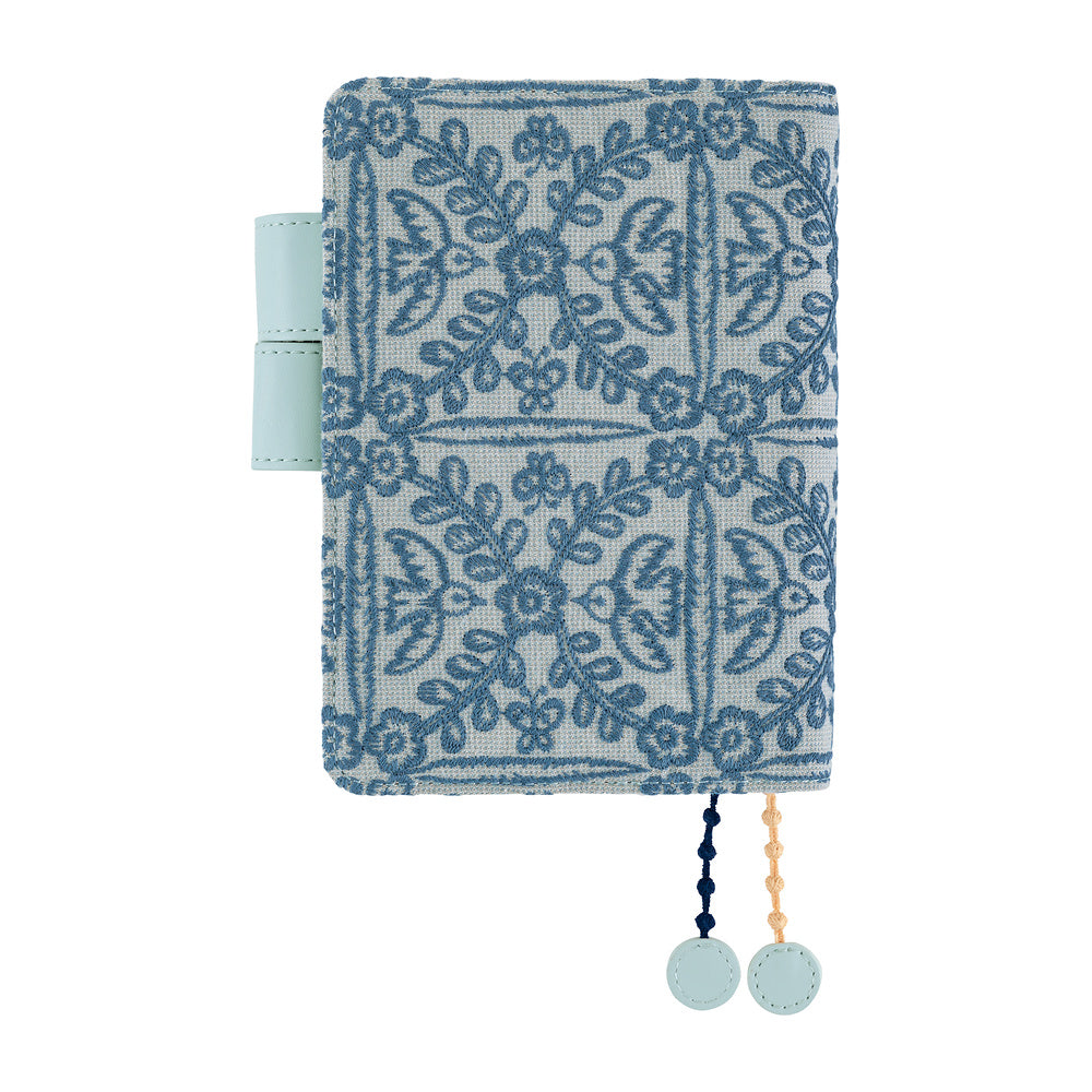 Hobonichi A6 planner cover in Blue floral embroidered fabric, with pale pen loop and two round charms.