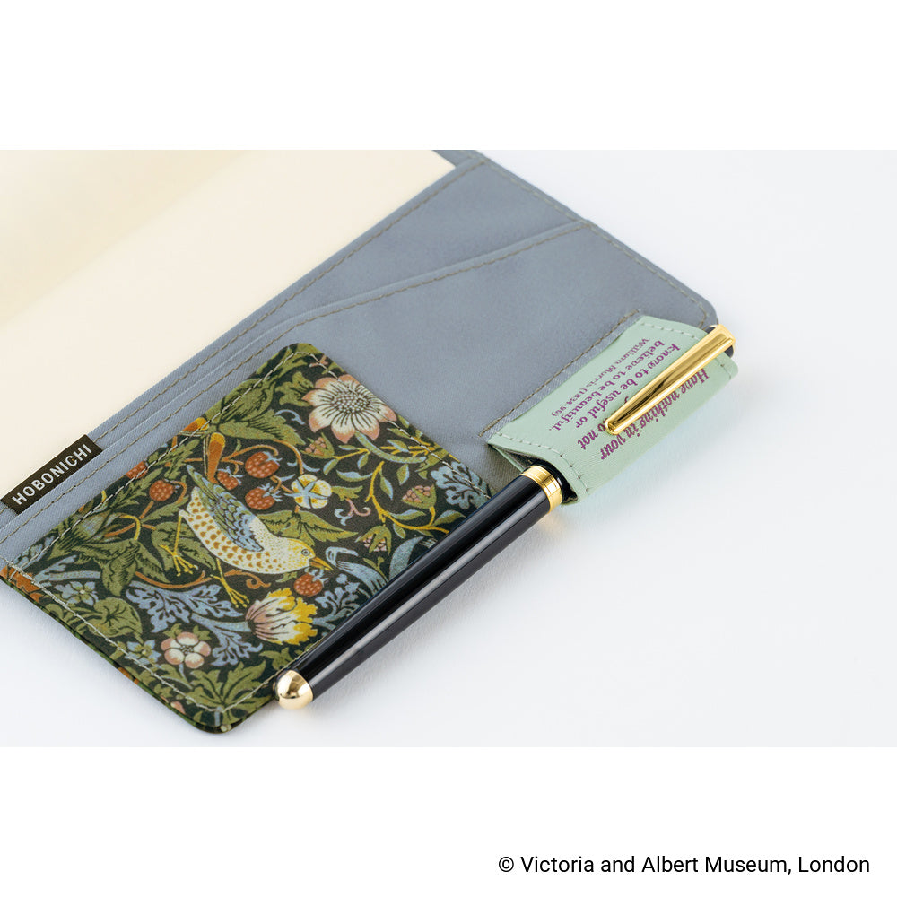 Open Hobonichi A6 book cover showing grey inner pockets, Dark Green floral bird panel and black pen with gold trim