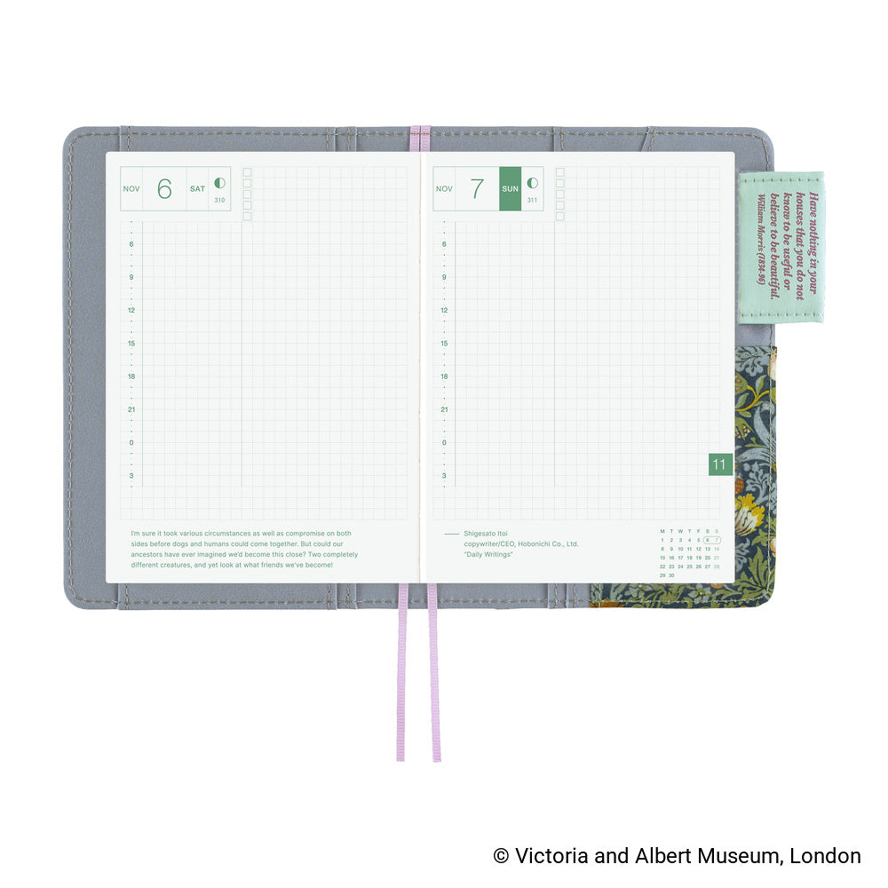 Open Hobonichi A6 planner in grey cover showing daily grid pages, pink bookmarks and floral inner lining