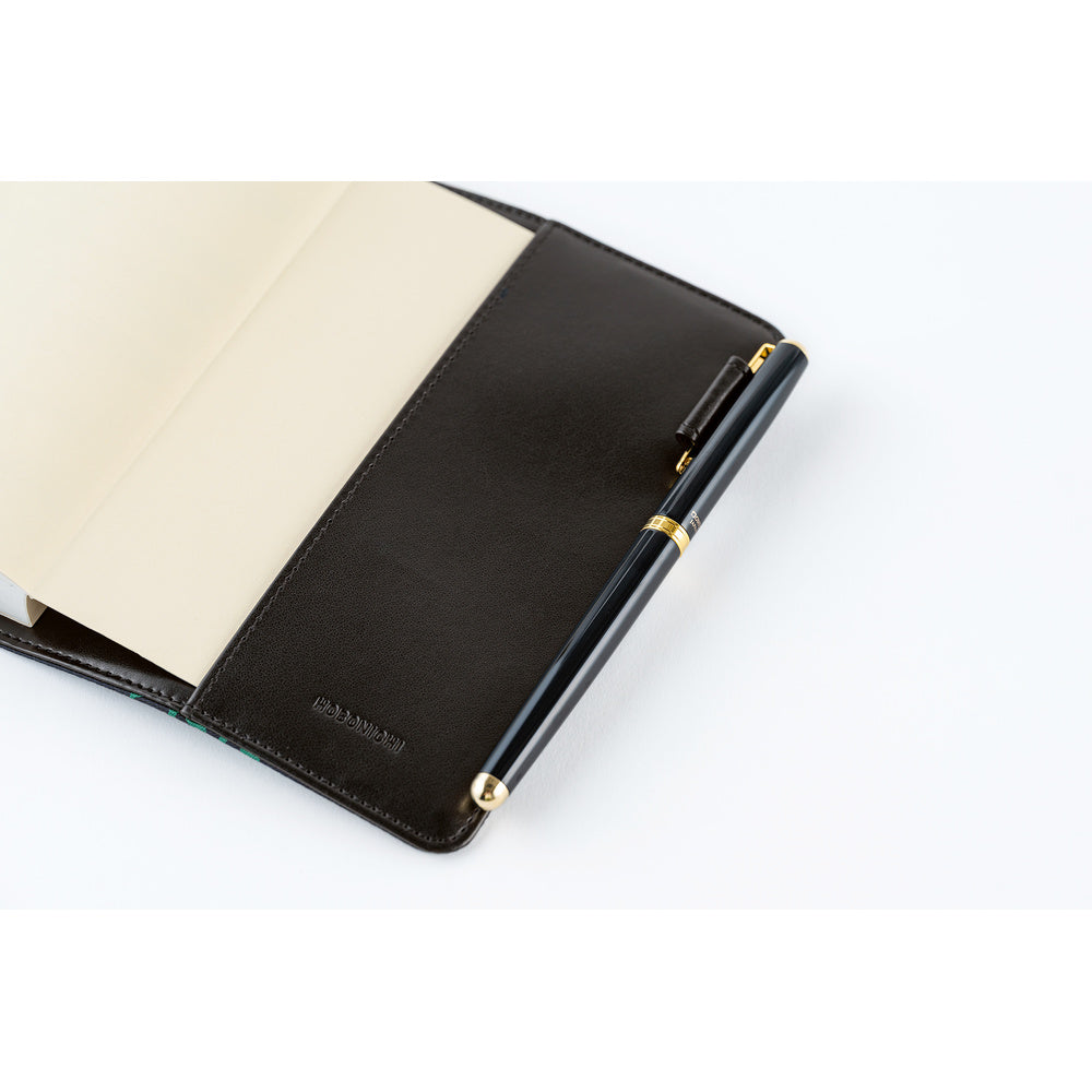 Open leather book cover with blank pages and a black pen with gold trim held in the side pen loop.