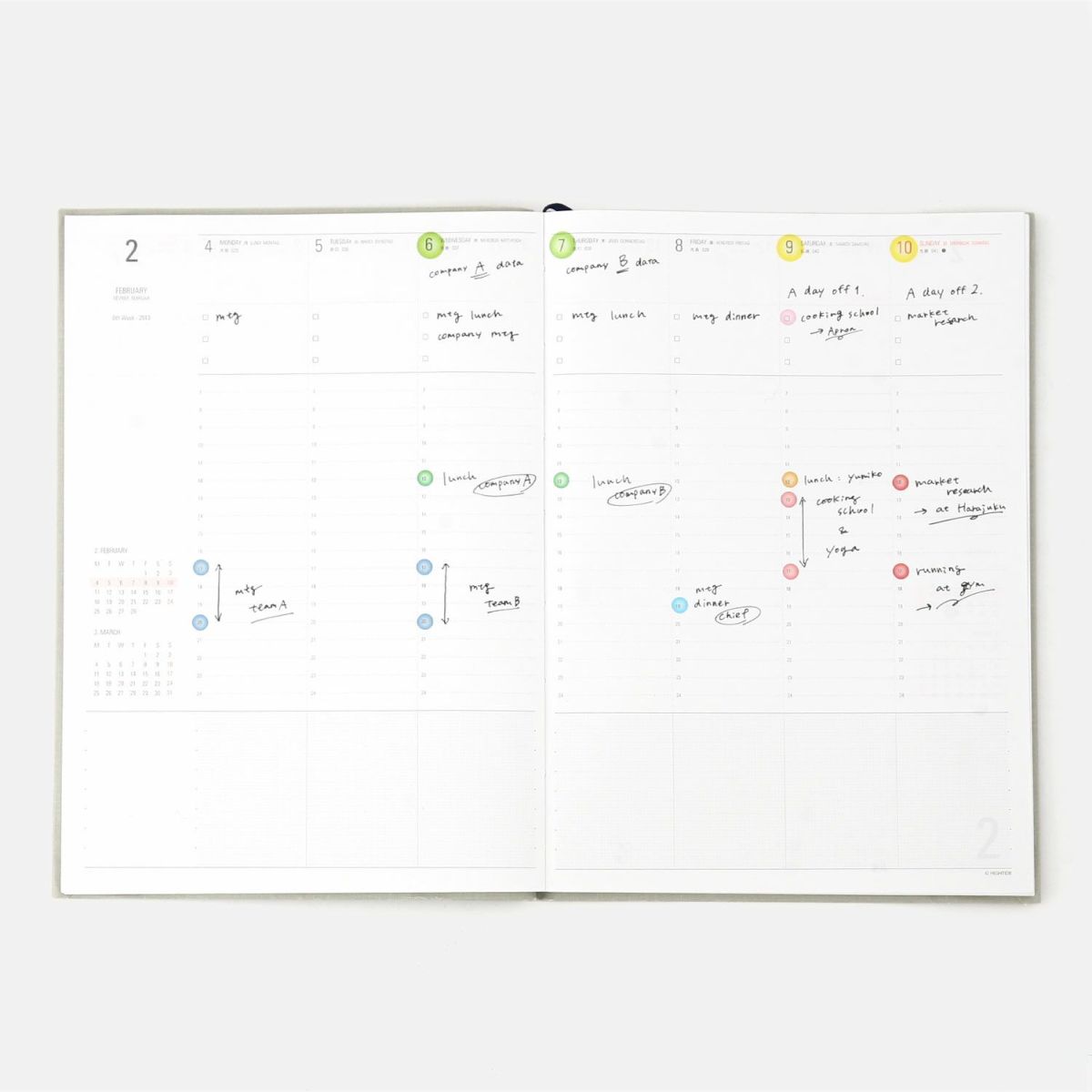 Open weekly planner spread with handwritten notes, marked with colorful see-through dot stickers on the timeline.