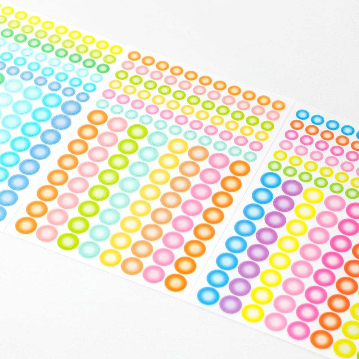 Angled close-up of sticker sheets covered in rows of small round dot stickers in blue, green, pink, orange and yellow.