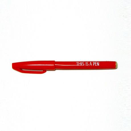 Red capped felt-tip pen by Noritake, printed with "THIS IS A PEN" in white on a white background.