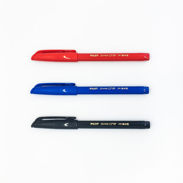 Three capped Pilot Super Petit pens in Red, Blue and Black, arranged in a row on a white background.