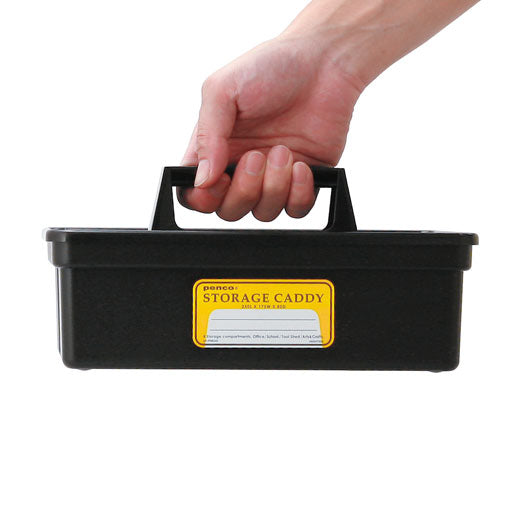 Hand carrying a Black Penco storage caddy by its handle, yellow front label reading Storage Caddy.