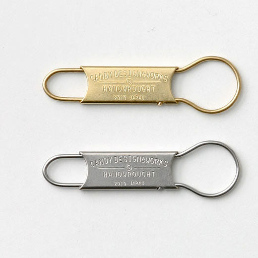 Two GORDON key rings, brass and stainless steel, with stamped Candy Design & Works lettering on flat plates.