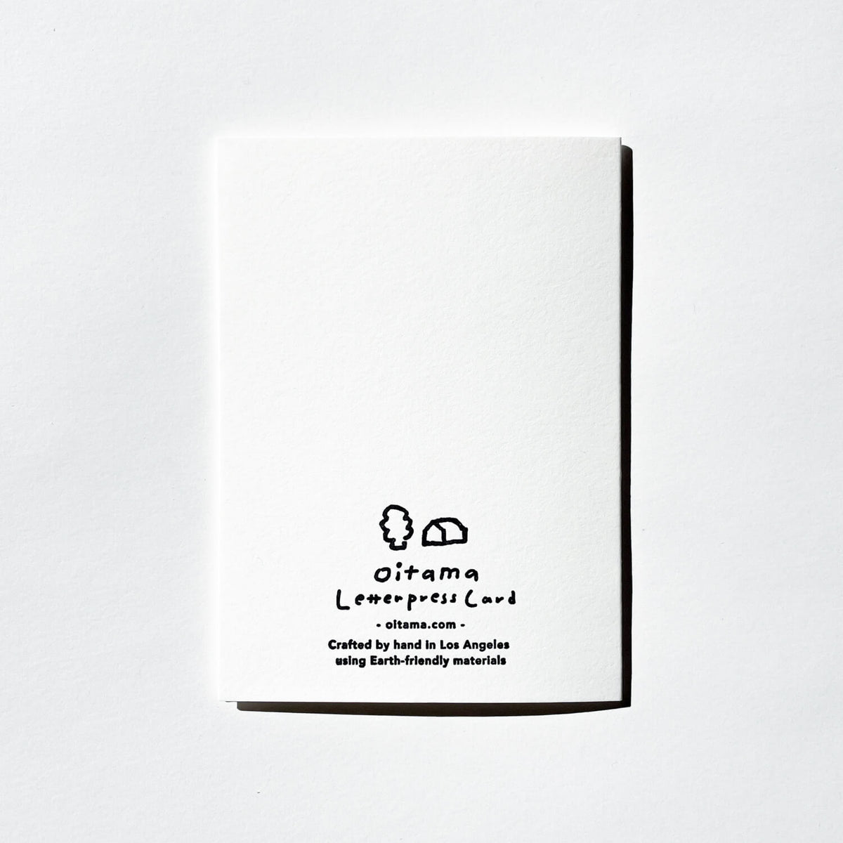 Back of an Oitama letterpress card, blank white with a small logo and printed credits at the bottom.